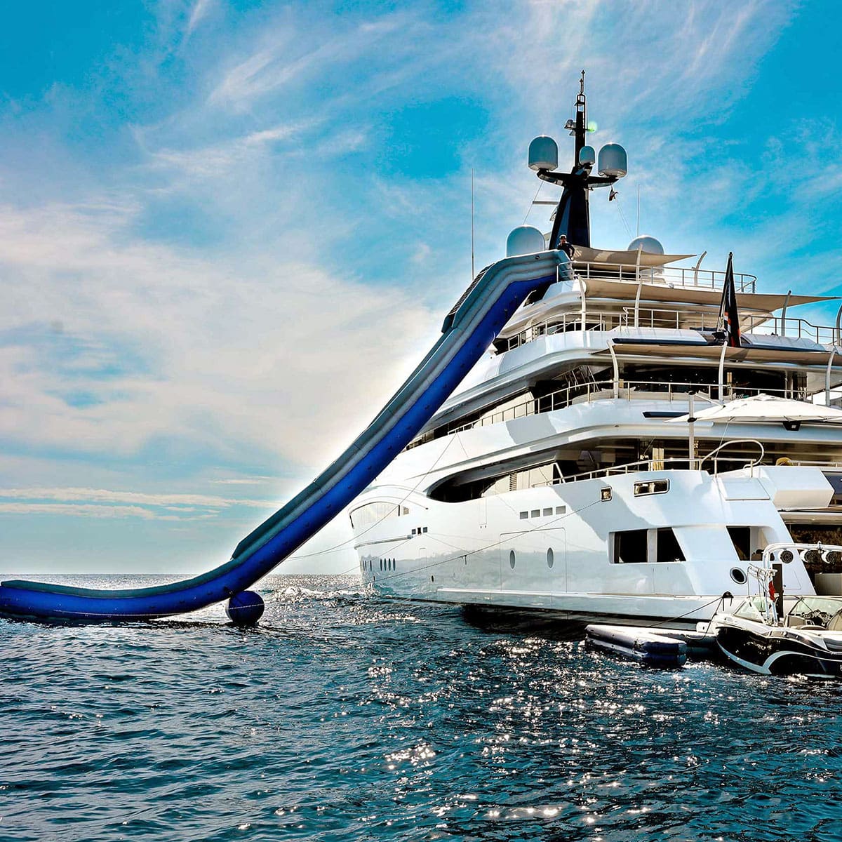A sytt with superyacht tenders and toys, including a water slide, in the middle of the ocean.