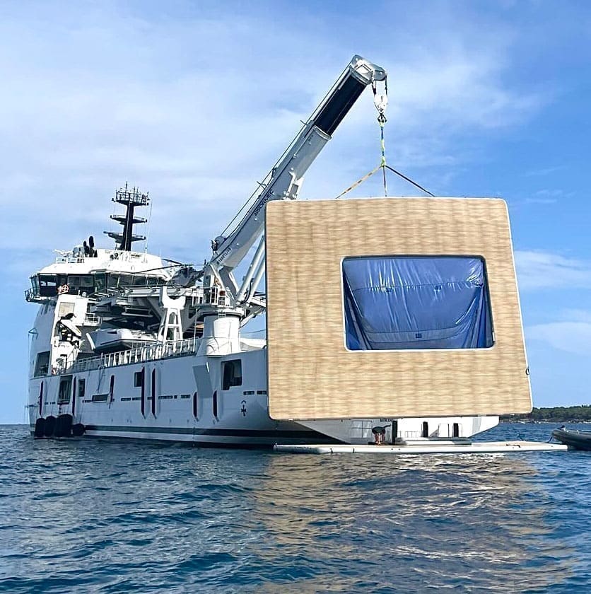 Platforms A boat with a large wooden box being lifted into the Inflatable Sea Pools.