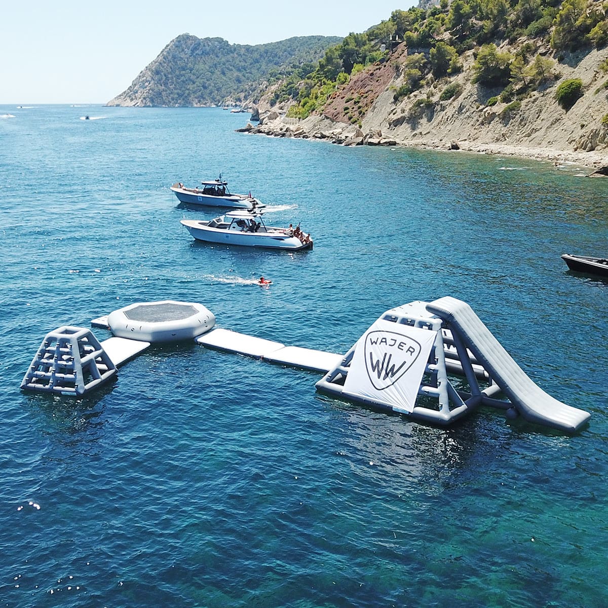 An inflatable aqua park set up close to the shoreline with small boats nearby