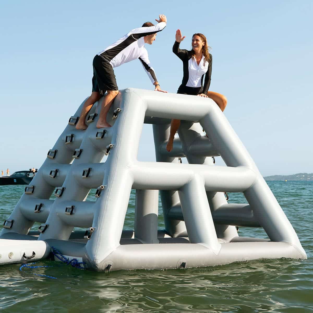 Two people high-five at the top of an inflatable climbing frame
