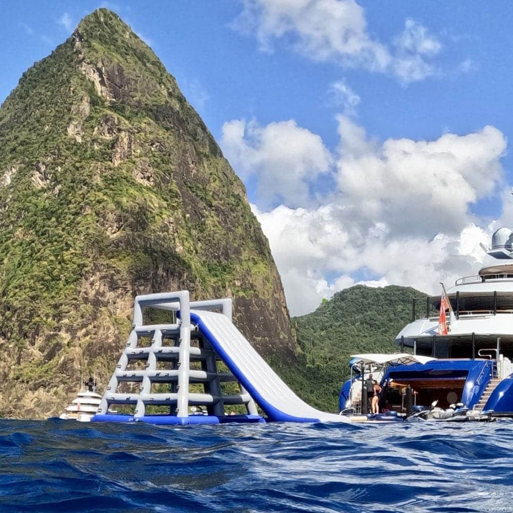 An Inflatable Aqua Park with a water slide in front of a mountain.