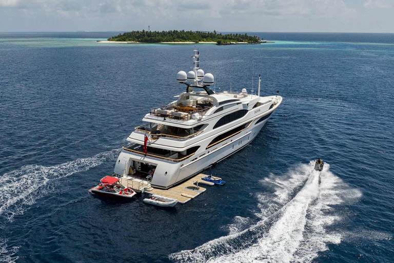 A large yacht in a remote Caribbean location being circled by a personal watercraft