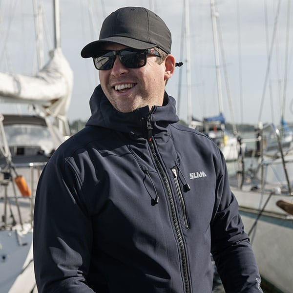 A man in a white shirt standing in front of a wooden wall, representing the team.